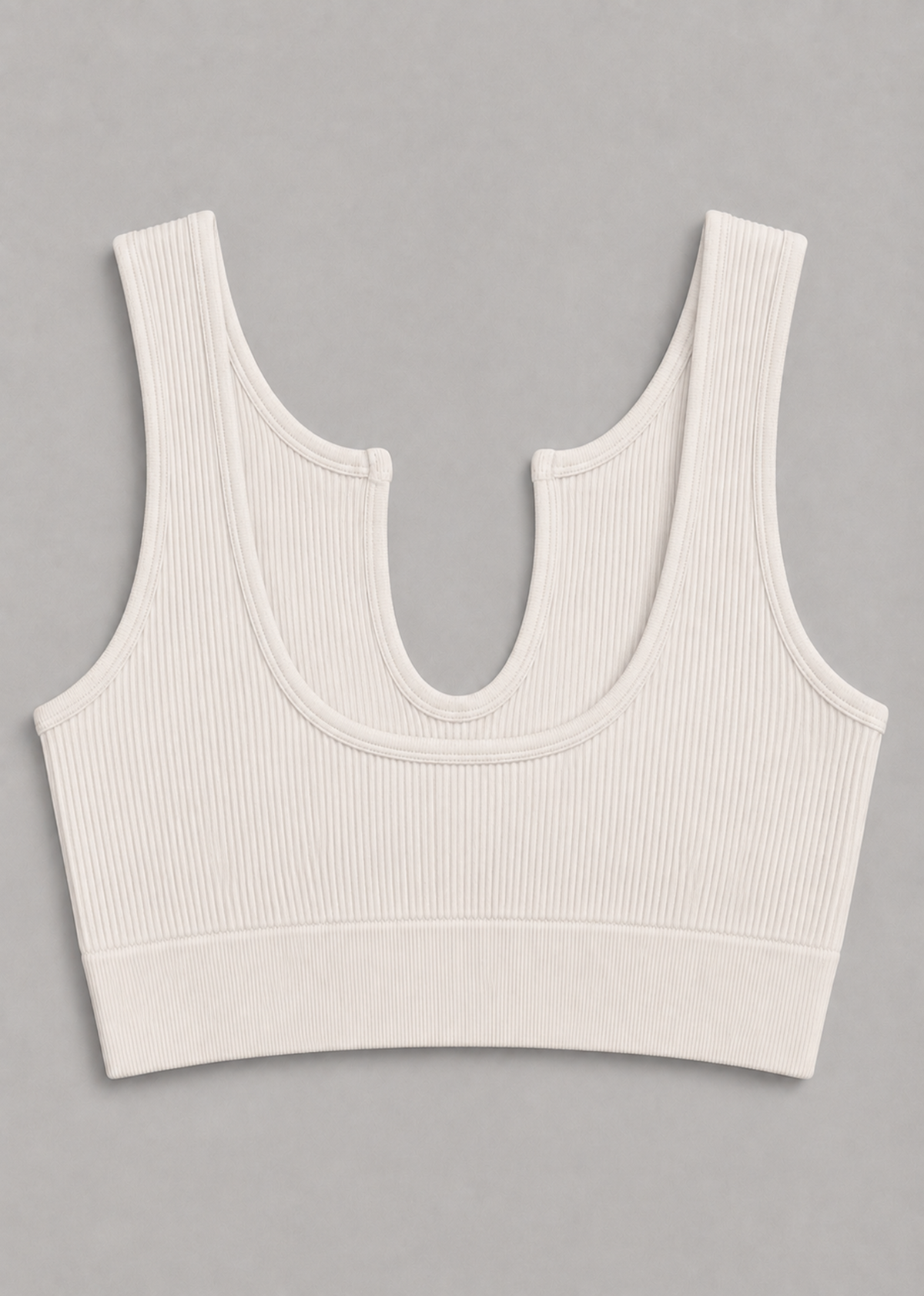 An off-white ribbed knit sports bra with a scoop neckline and double shoulder straps, laid flat on a neutral gray background.