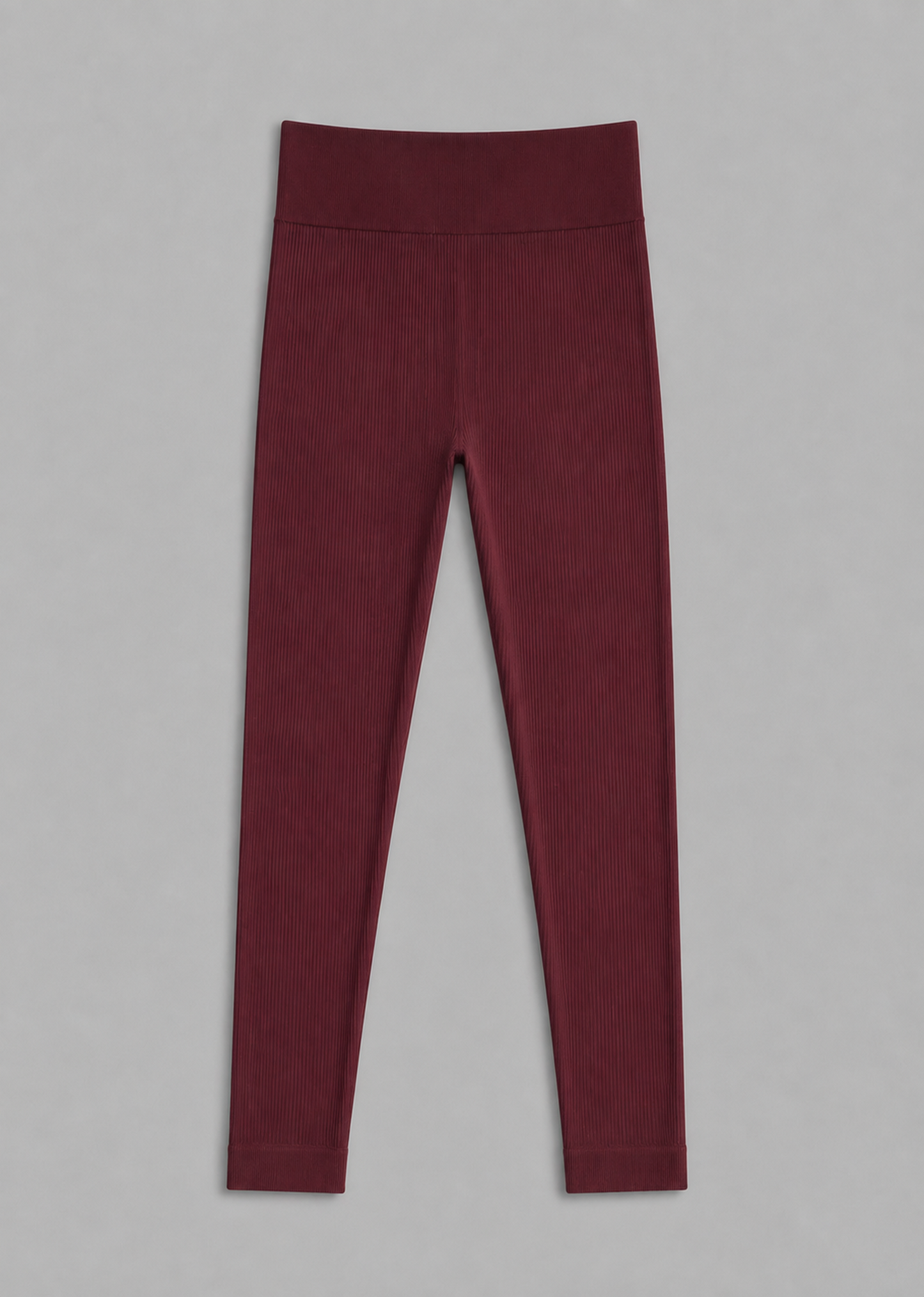 A pair of high-waisted, full-length leggings in a deep burgundy color, laid flat against a neutral gray background.