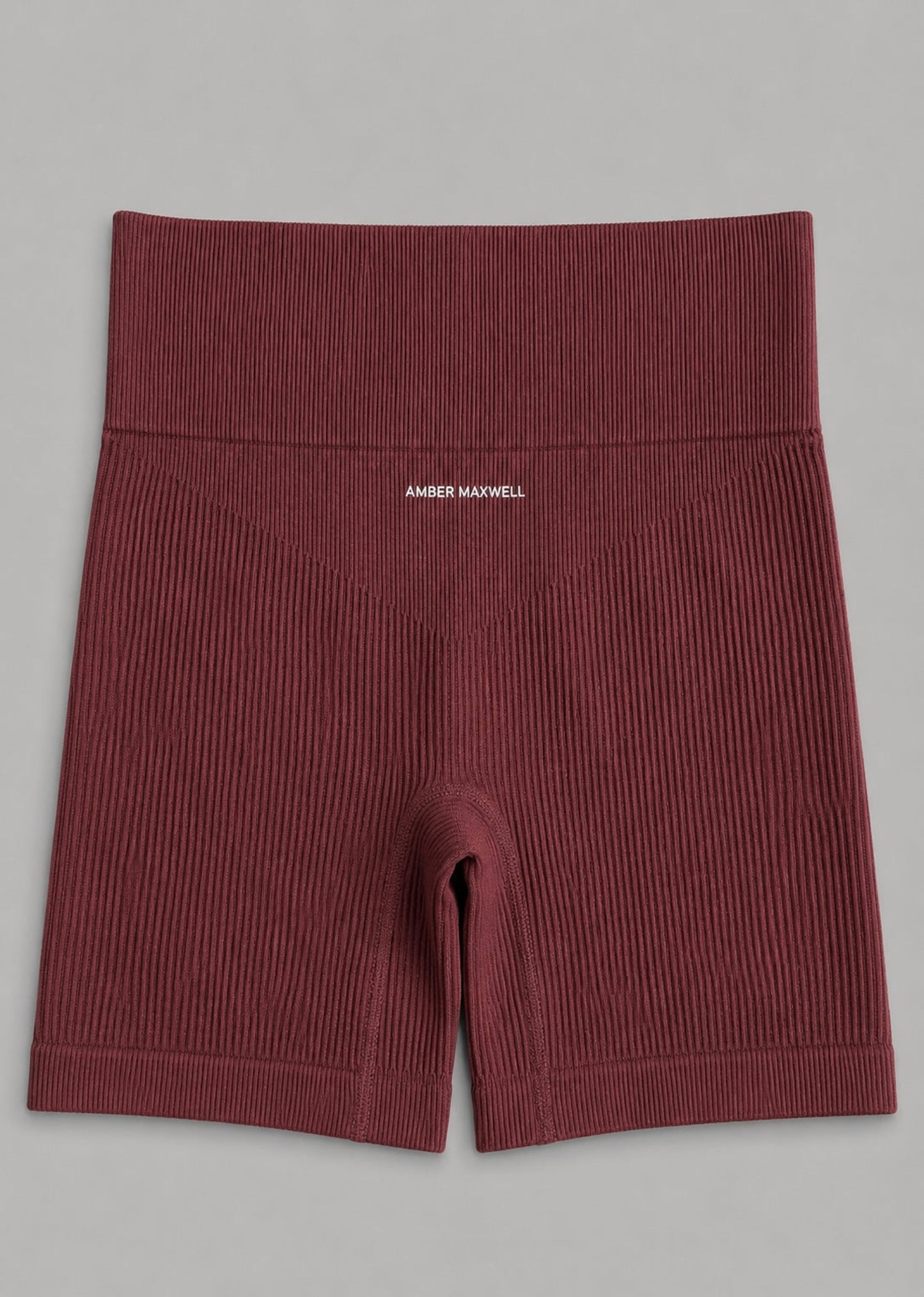 A pair of ribbed knit boxer briefs in a deep burgundy red, featuring a wide elastic waistband with the brand name 'AMBER MAXWELL' printed in white on the front, laid flat on a neutral gray background.