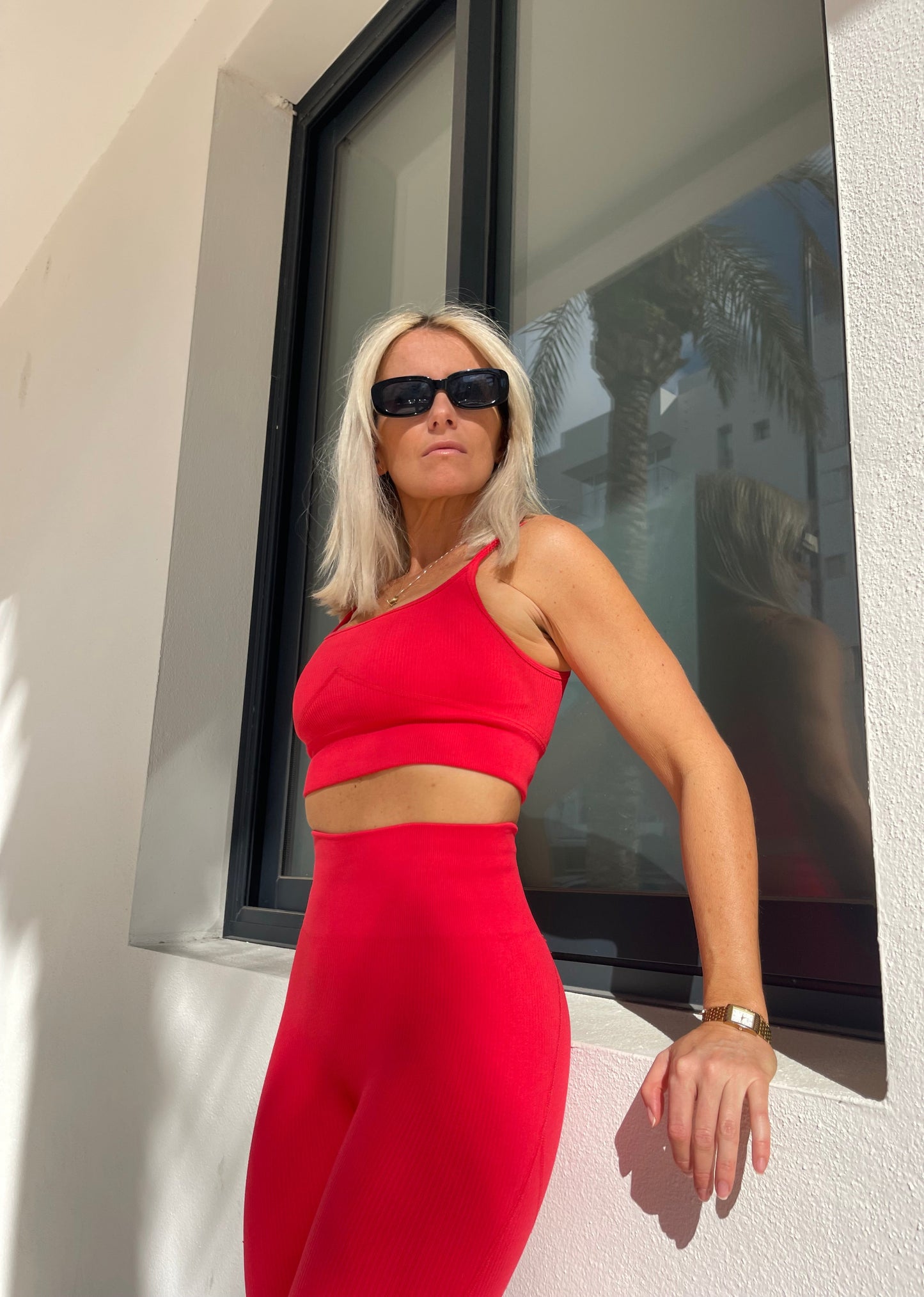Model walking in Ibiza wearing Amber Maxwell Marina crimson crop top and Marina leggings in Ibiza 